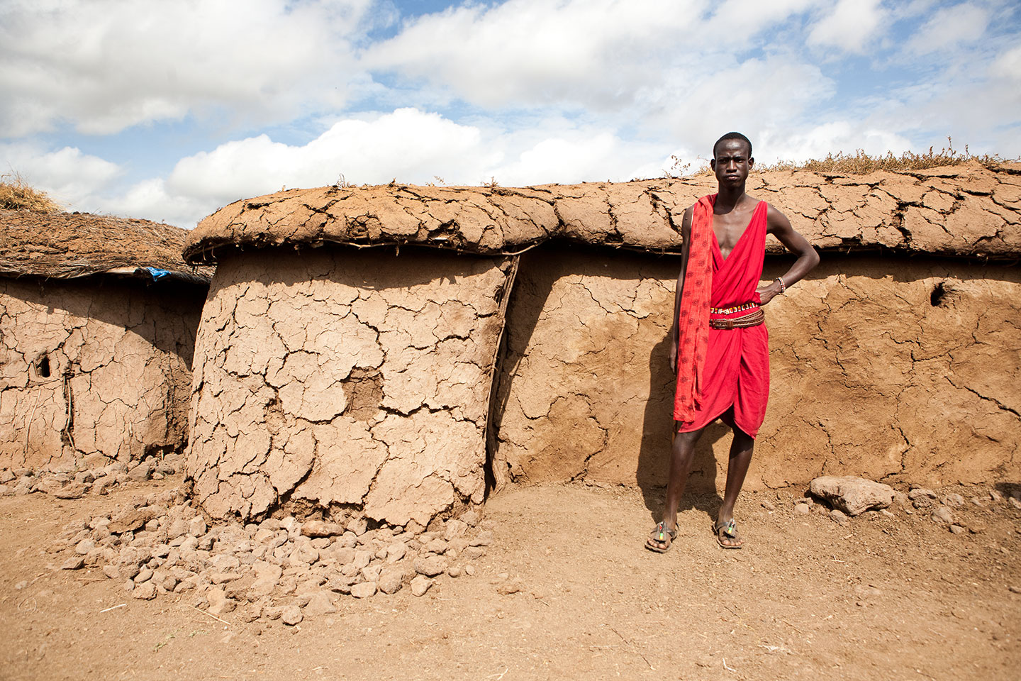 A Maasai male next to a clay hut in a Maasai village in Kenya, Africa