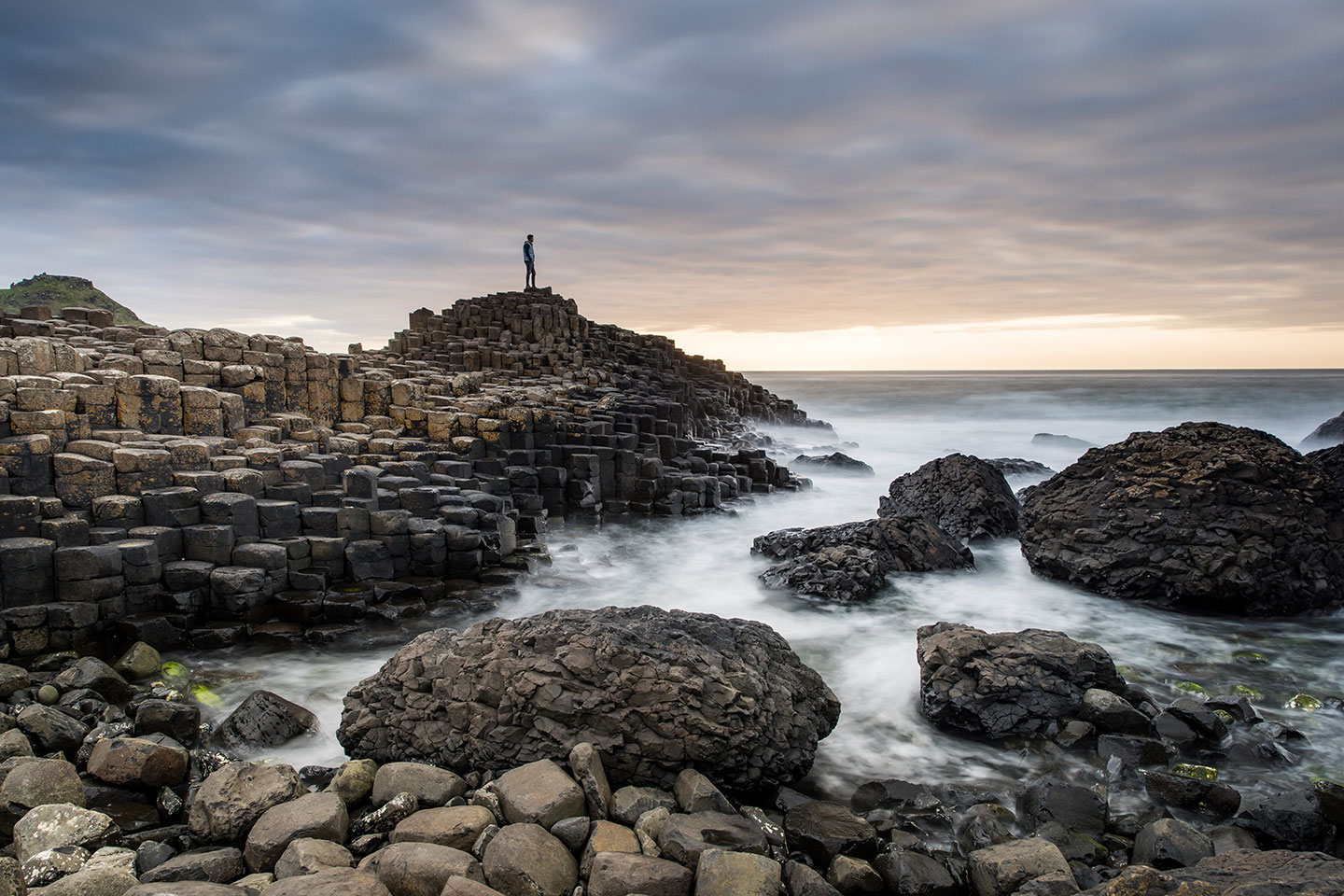 Person standing on top of the basalt columns of Giant's Causeway, Northern Ireland