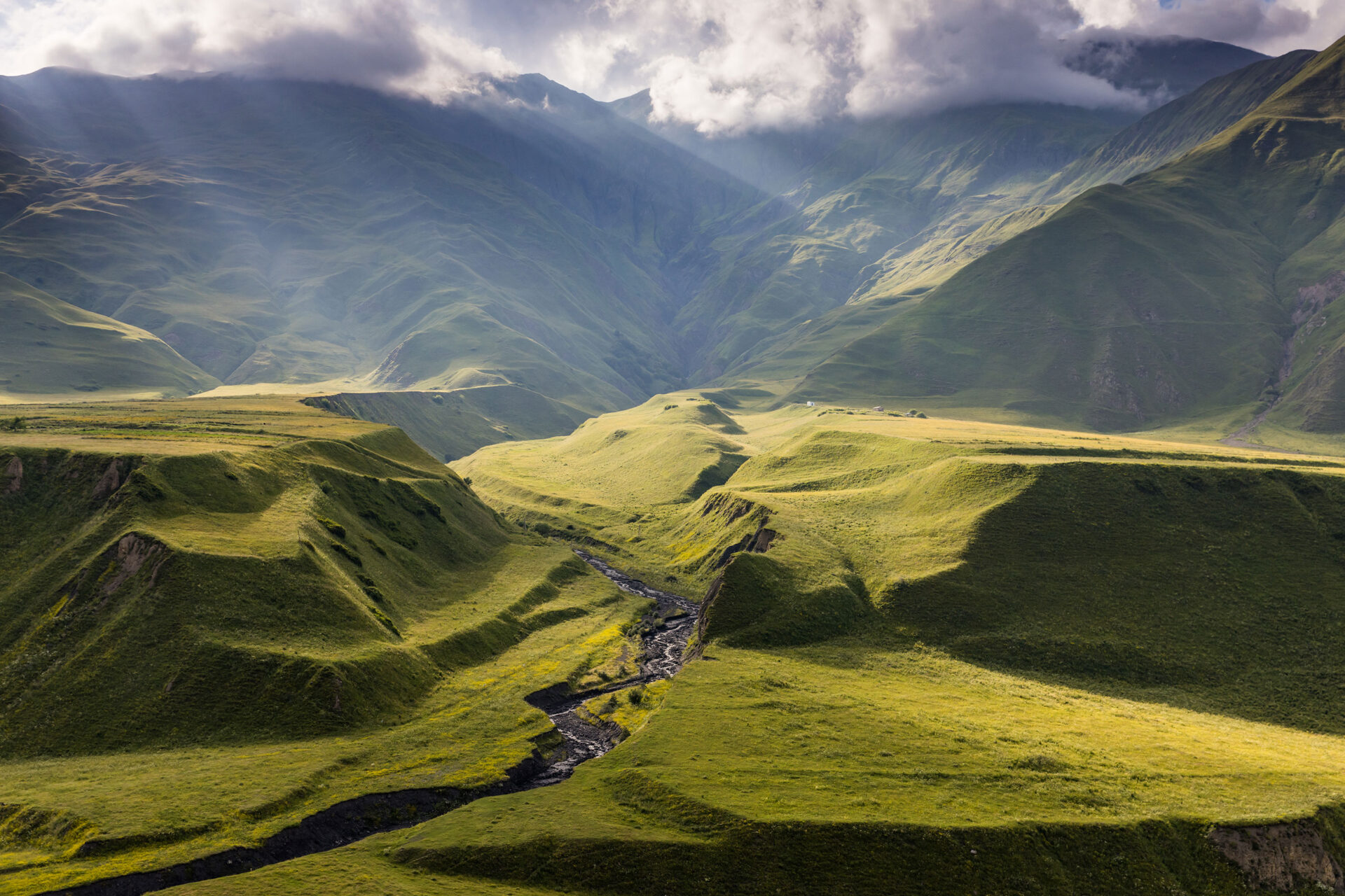 Sunlight hitting a green valley in the Kazbegi area of Georgia
