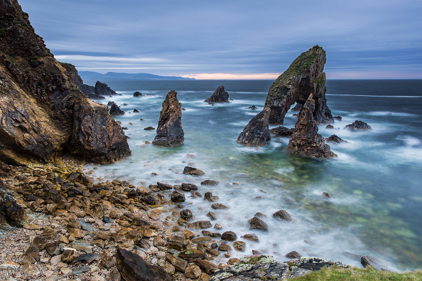 Crohy Head Sea Arch rock formations coming out of the water at sunset, Ireland