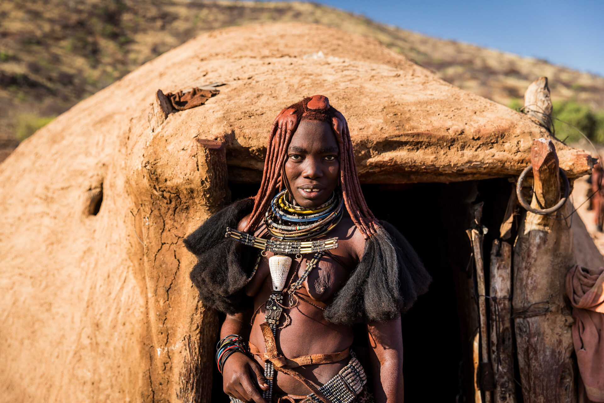 Young Himba tribe girl near a hut in her village, Namibia
