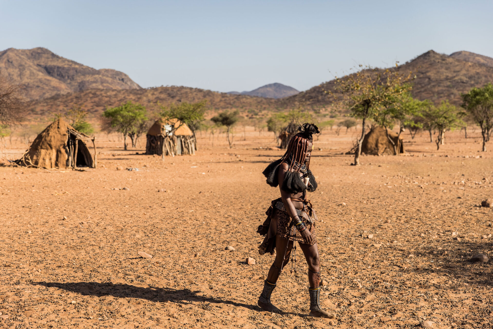 Himba tribe girl walking through a village in Namibia